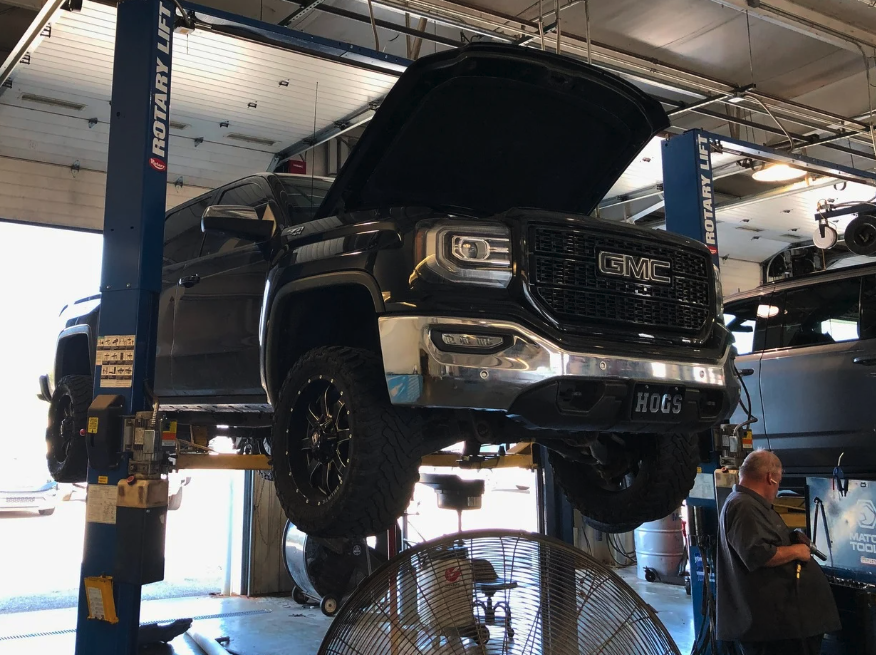 GMC truck elevated on service lift at Crain Buick GMC in Springdale with technician preparing for holiday maintenance
